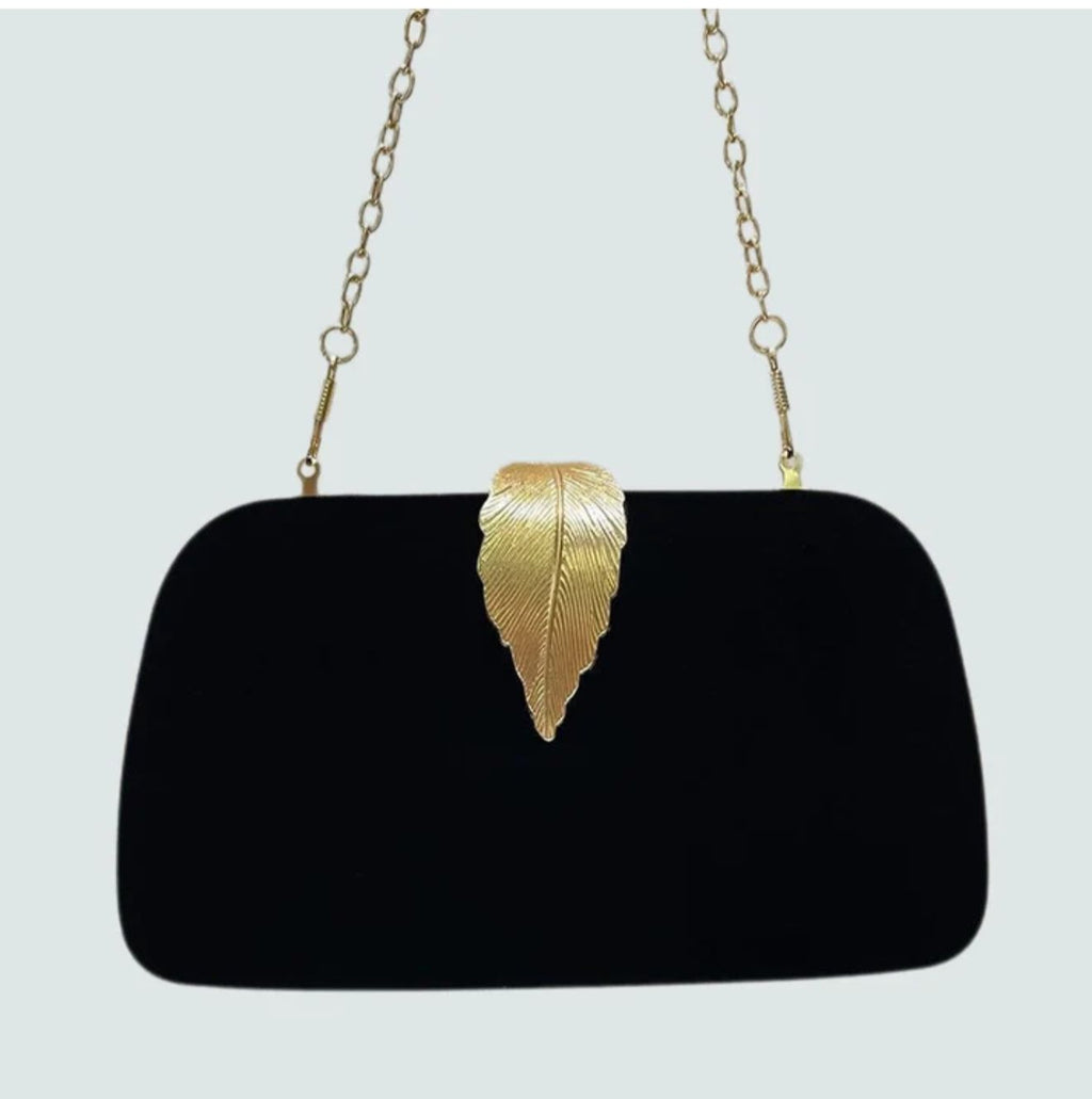 Black velvet clutch bag with gold leaf clasp held in hand
