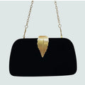 Black velvet clutch bag with gold leaf clasp held in hand